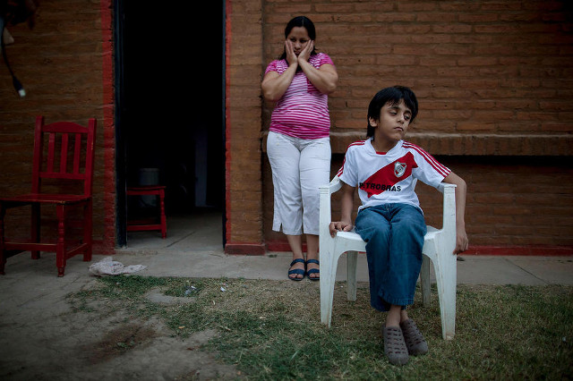 Silvia Alvarez leans against her home while keeping an eye on her son, Ezequiel Moreno, who was born with hydrocephalus, in Gancedo, in Chaco province, Argentina, April 1, 2013. Chaco provincial birth reports show that congenital defects quadrupled in the decade after GM crops arrived. CREDIT: Natacha Pisarenko/AP